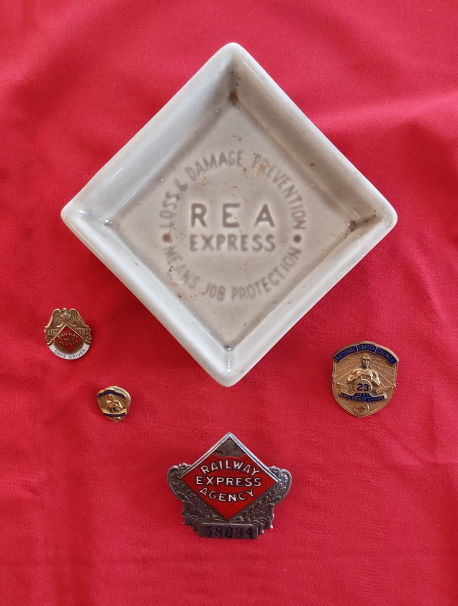 Family keepsakes of Jimmy Fitzgerald's family - small ceramic tray with hat badge in front and flanked left and right by safe driving pins. Photo courtesy of the Little Falls Historical Society.