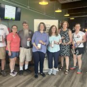From left to right: Tom Hennessy of Kessler Brewing Company; Stacey Michaels and Rich Michaels of Second Act Spirits; Teresa Casey, executive director of the Capital Craft Beverage Trail; Jodie Rodriguez of Eisenadler Brauhaus; Sen. Pat Fahy; Sarah Rosemyer of Erie Canal Distillers; and Montgomery County Executive Pete Vroman gather at Second Act Spirits in Amsterdam to celebrate the expansion of the Capital Craft Beverage Trail into Montgomery, Fulton and Schoharie counties.