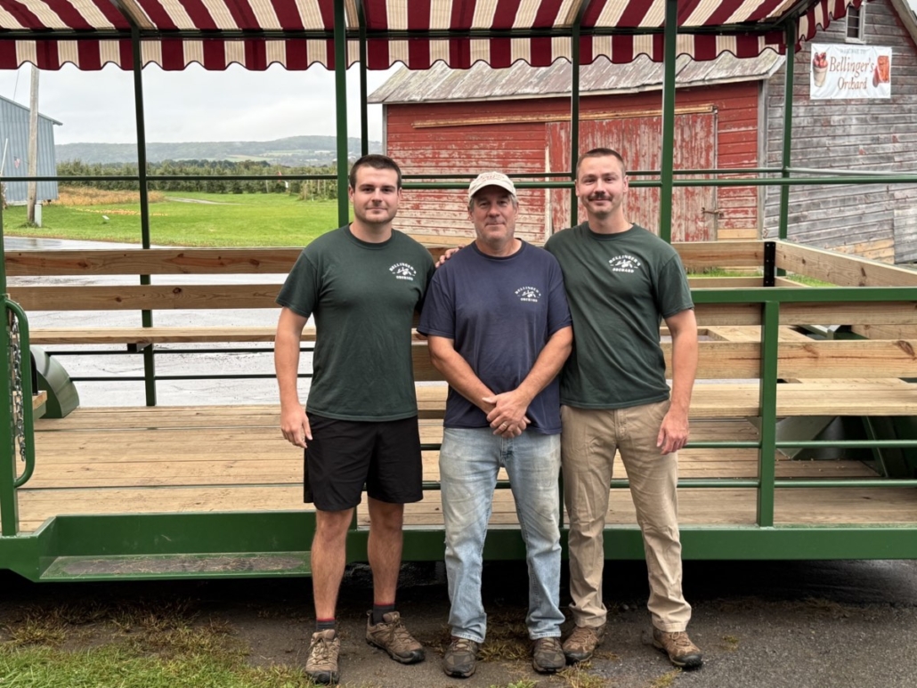 Ken Coyne, center, stands with his sons, Josh and Ian, in front of Bellinger’s Orchard’s new accessible hay wagon. Ken Coyne, center, stands with his sons, Josh and Ian, in front of Bellinger’s Orchard’s new accessible hay wagon.