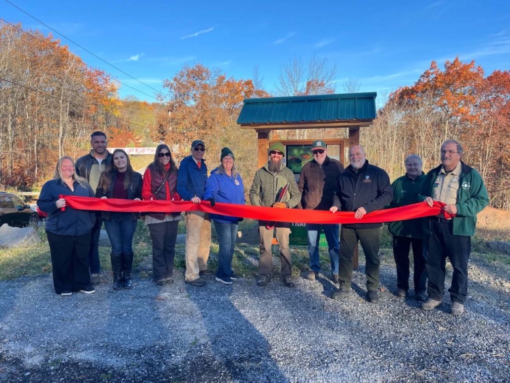 Montgomery County officials join Landis Arboretum staff and volunteers for a ribbon cutting ceremony celebrating a new trailhead information kiosk at the west entrance of the Waterfall Trail.